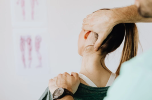 A massage therapist treating a woman's injured neck;  photo by Karolina Grabowska, via Pexels.com.